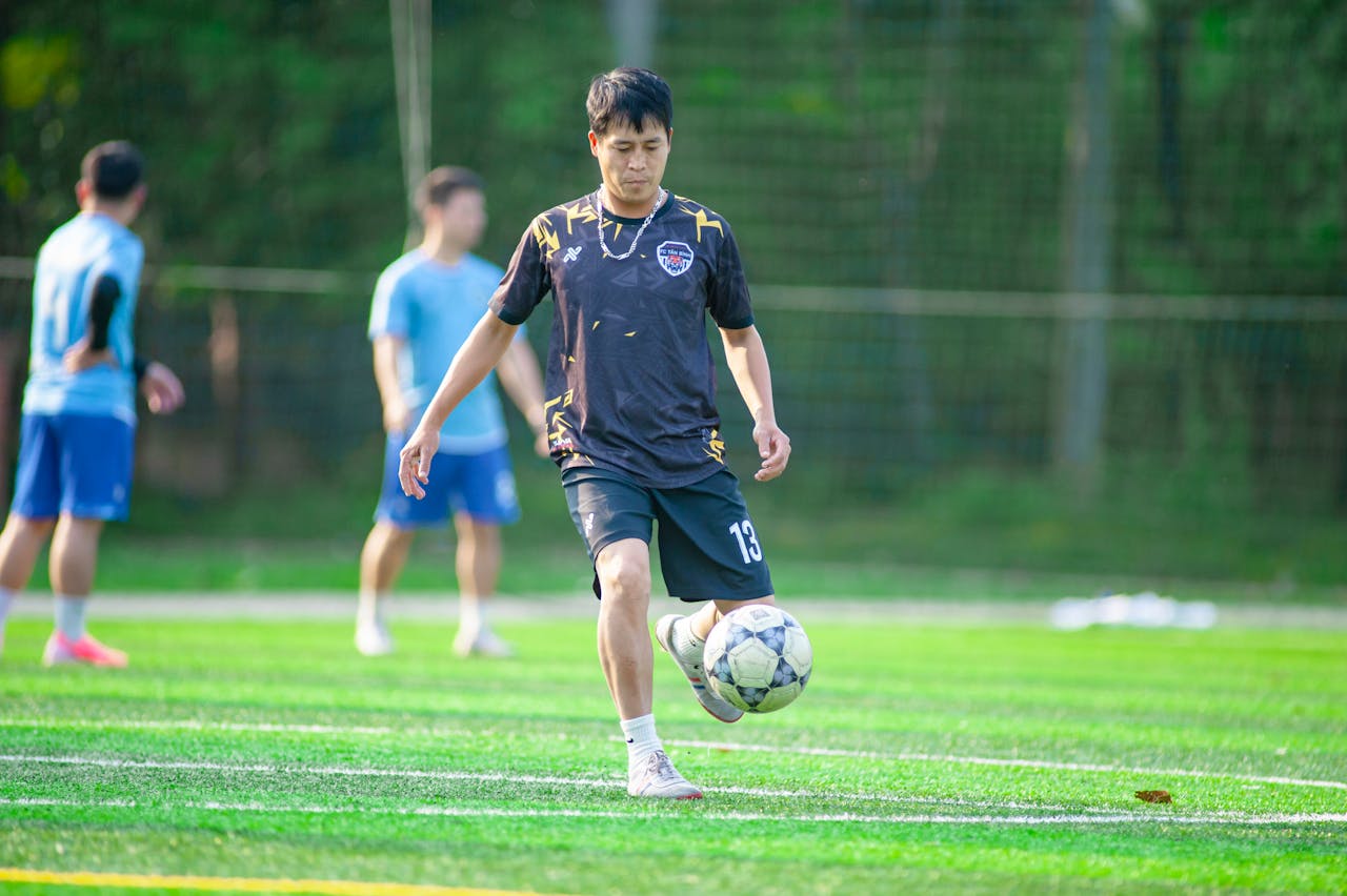 story-img Group of young men playing soccer on a vibrant green field in Hanoi, Vietnam.